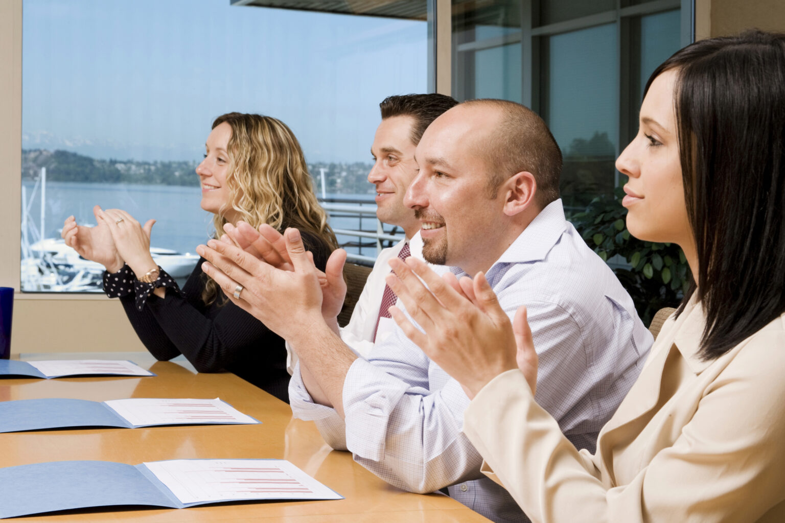 Sales team building workshop with team members smiling and collaborating with their trainer. The trainer is facilitating activities designed to strengthen team dynamics and improve sales performance, and the group is visibly enjoying the interactive and engaging session