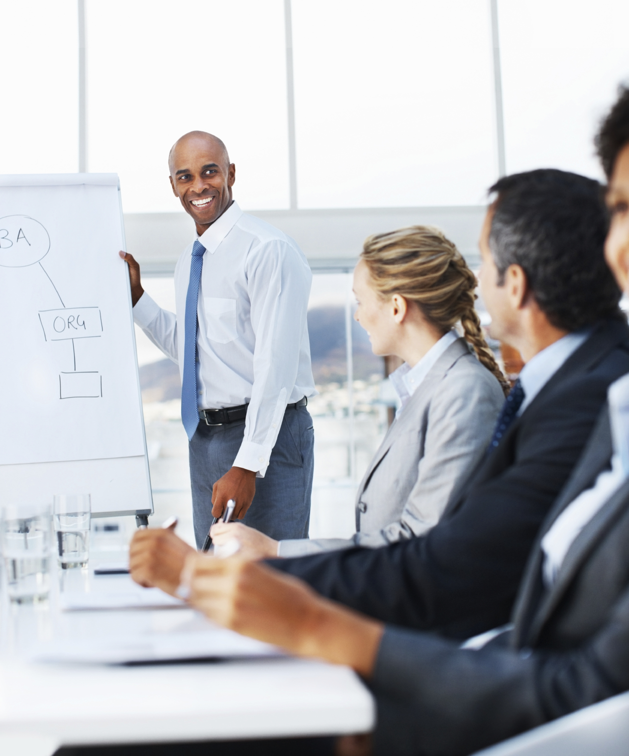 Sales management training workshop with professionals smiling as they listen to the trainer. The session focuses on optimizing sales management processes, with participants engaged in discussions and exercises designed to enhance their management skills and strategies