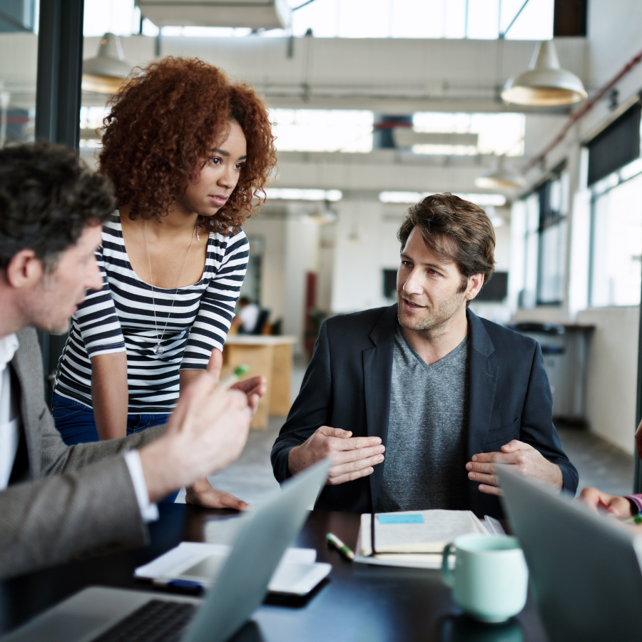 A man sitting at a table, speaking with his team during a core sales meeting.