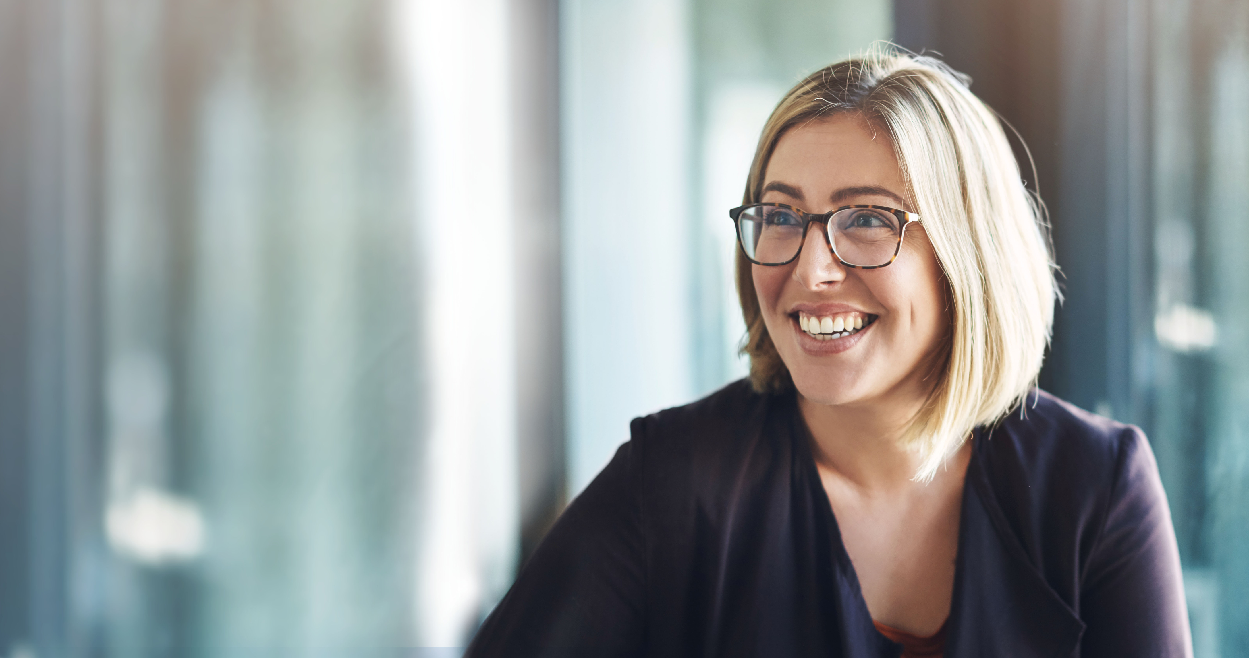 A woman smiling at a table during a human-centered leadership session, with the camera focused on her.