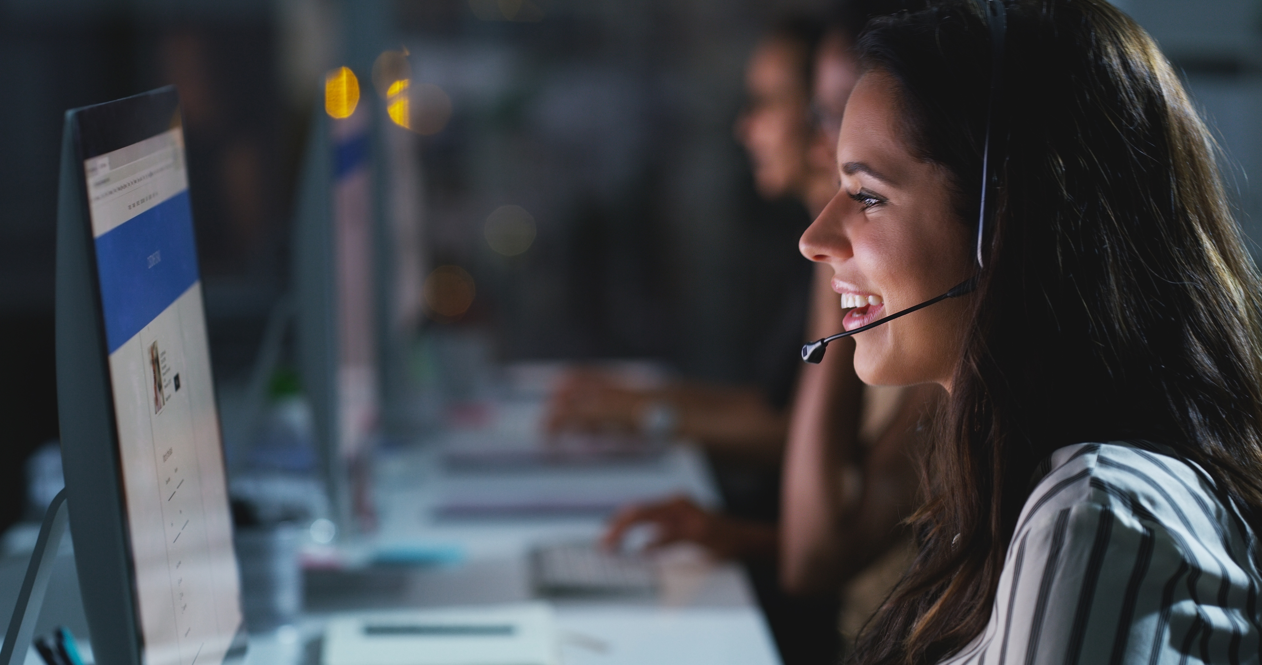 A woman smiling at her computer, engaged in a conversation with a client during a remote sales call.