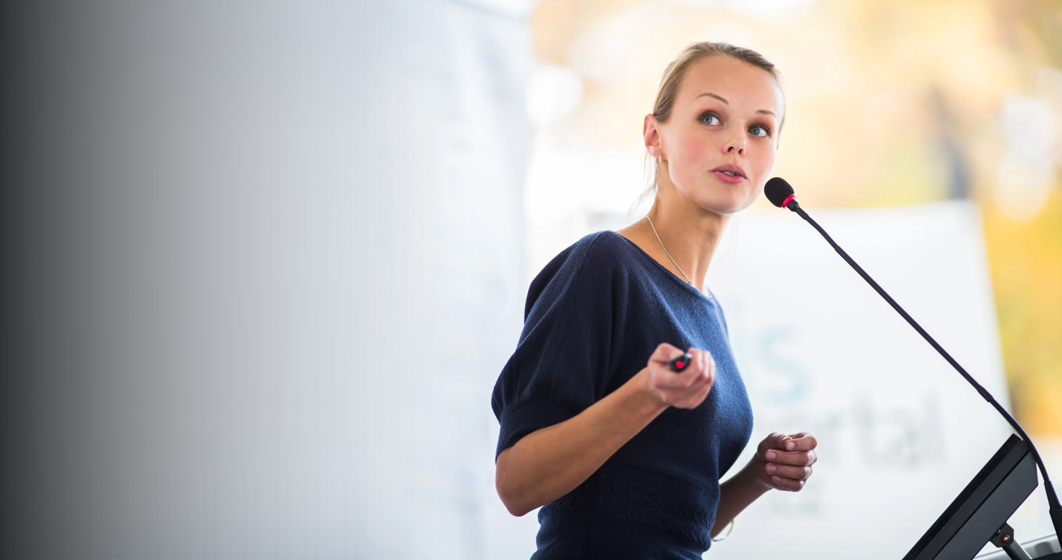 A woman preparing to present in a High Performer Programme, speaking to the audience while holding a clicker in her hand.