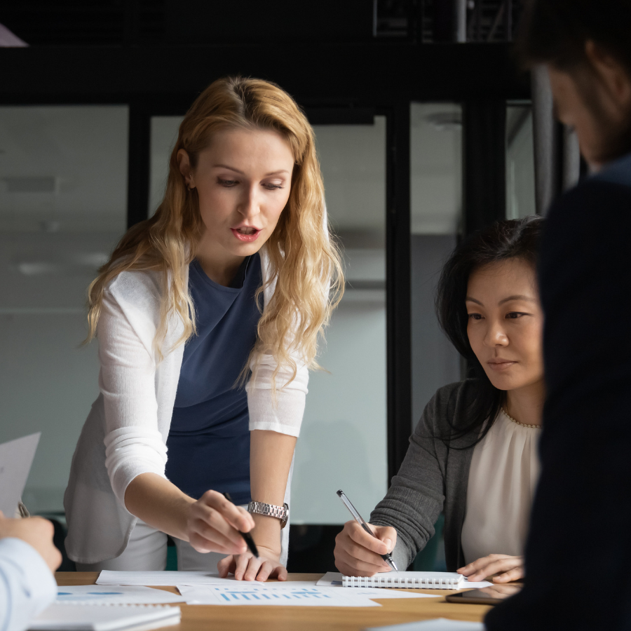 A woman with her team, holding a pen and about to write on a large piece of paper during a Key Account Management session.