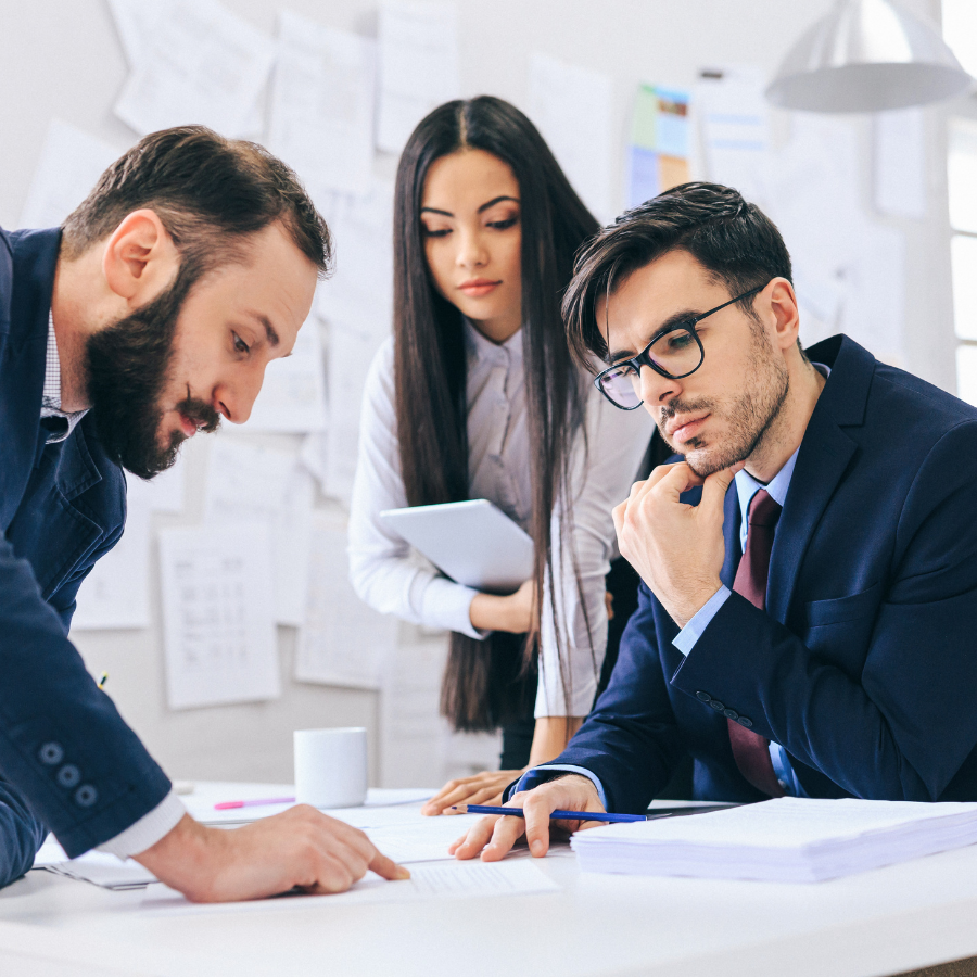 A man deep in thought, surrounded by his team during a Sales Management discussion.
