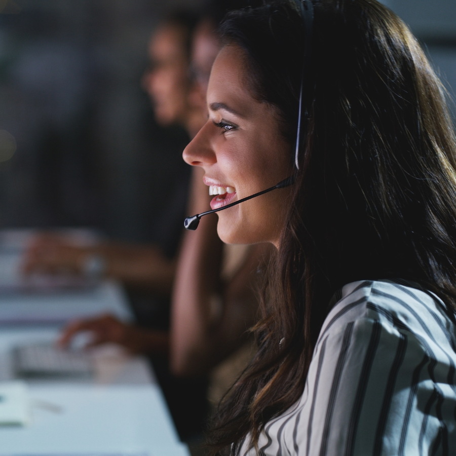 A woman smiling at her computer, engaged in a conversation with a client during a remote sales call.