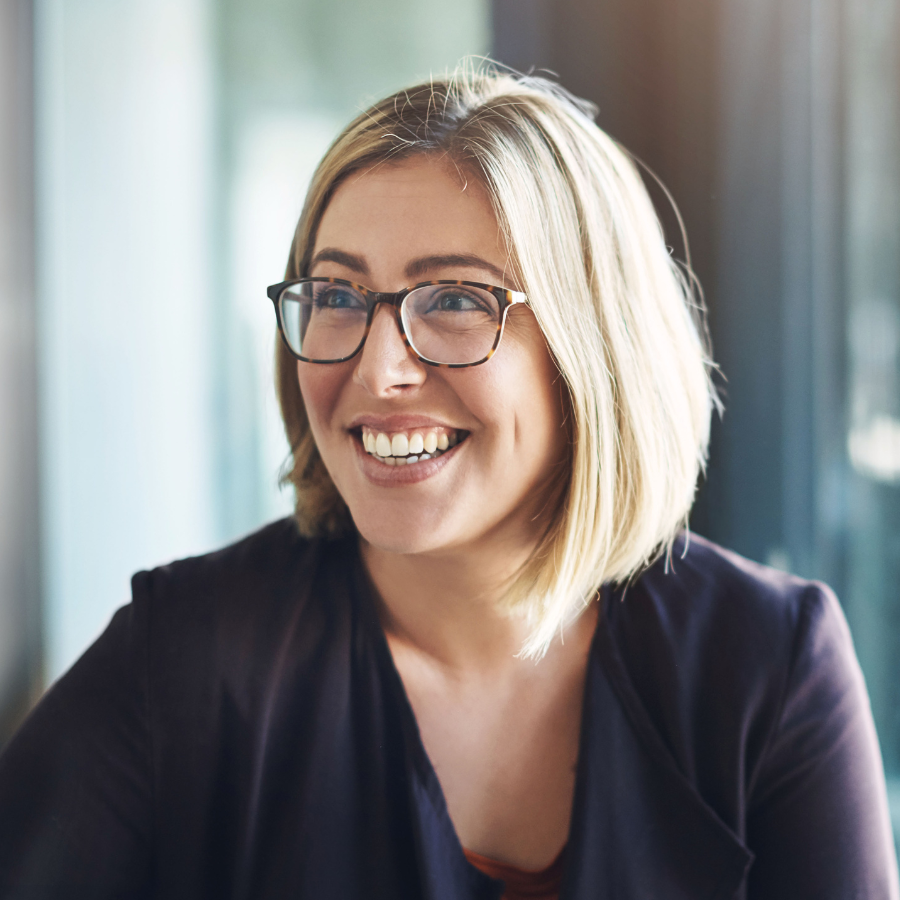 A woman smiling at a table during a human-centered leadership session, with the camera focused on her.